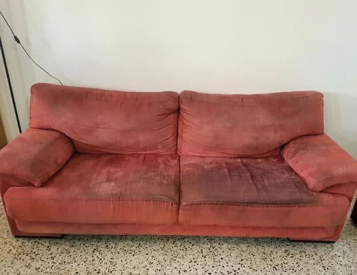 Worn red suede sofa with soiled seat cushions before cleaning